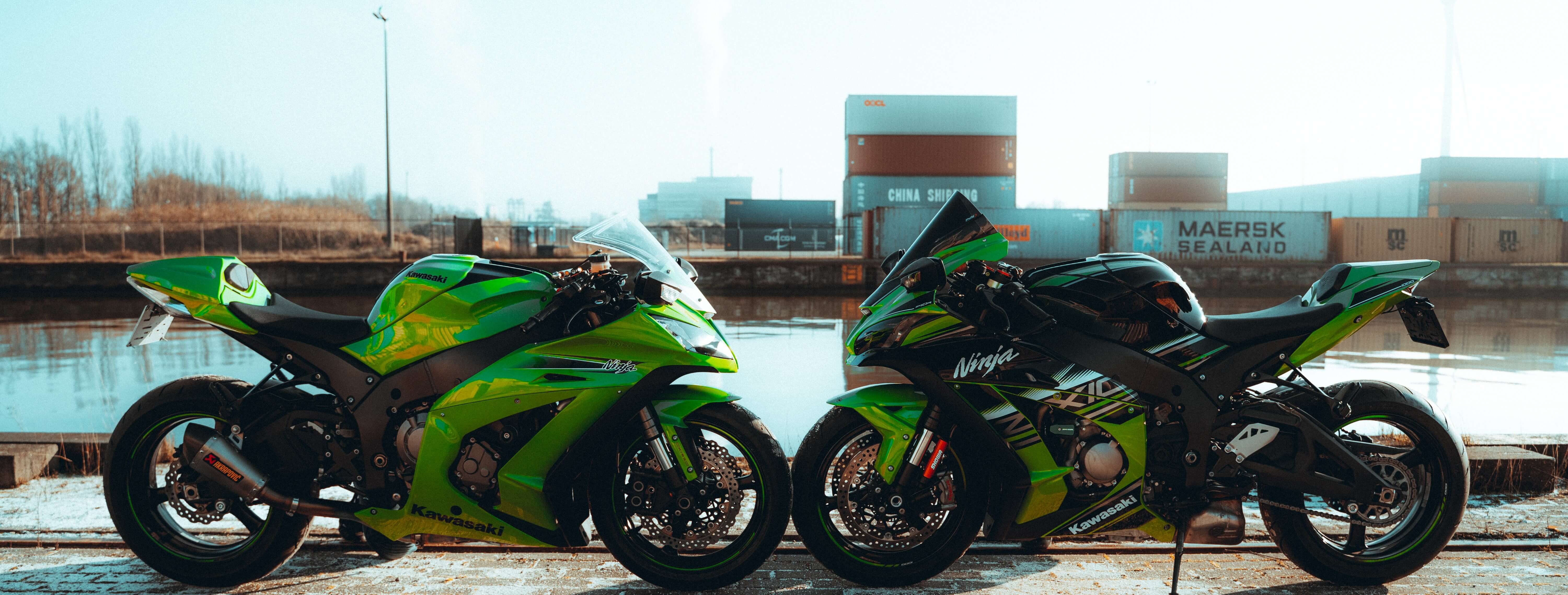 two ninja motorbikes facing each in the background there is shipping containers 